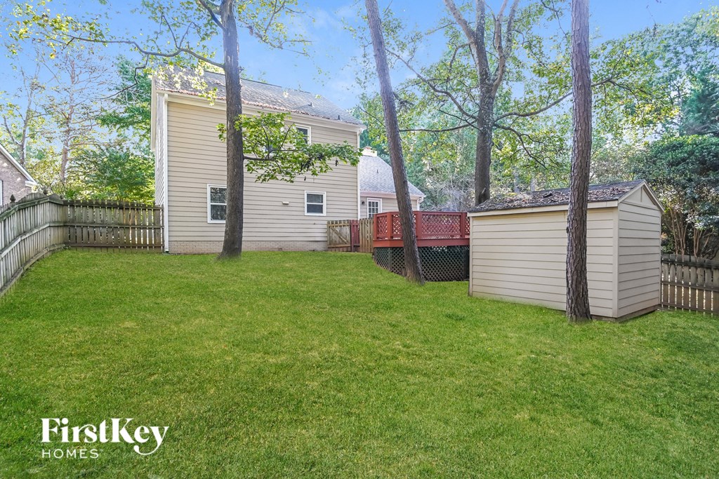 a backyard with a shed and a hot tub and a fence