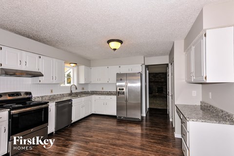 A kitchen with white cabinets and a stainless steel refrigerator.