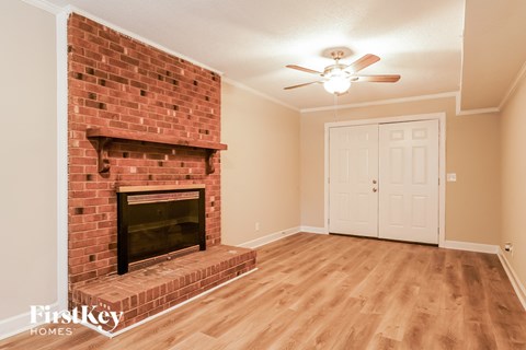 A room with a brick fireplace and wooden floors.