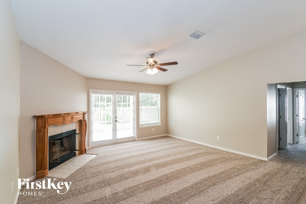 A spacious room with a fireplace and a ceiling fan.