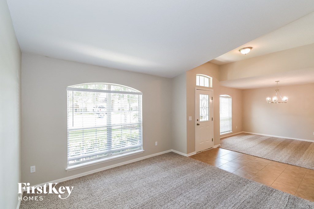 A spacious room with a large window and a door leading to another room.