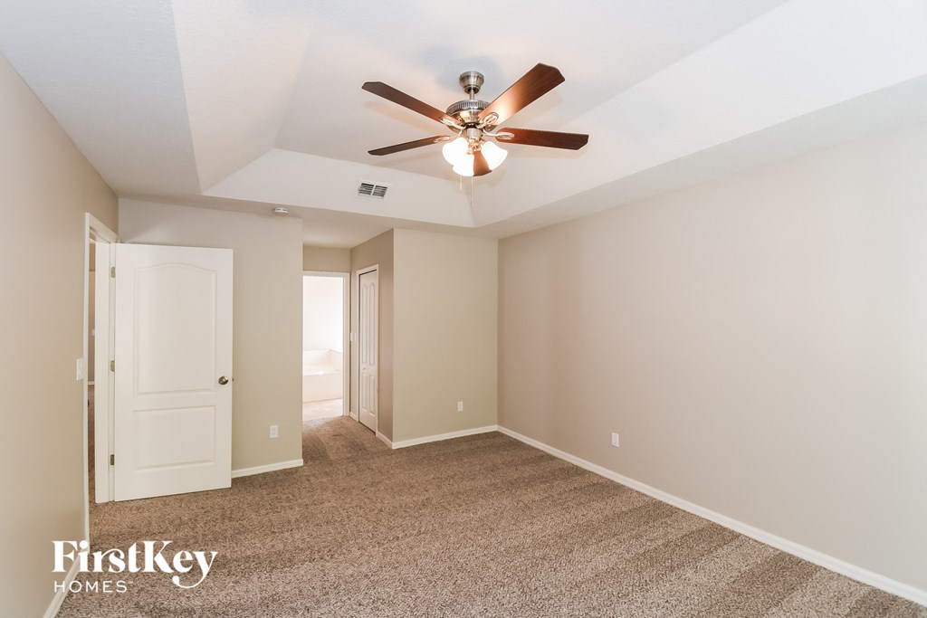 A spacious room with a ceiling fan and carpeted floor.