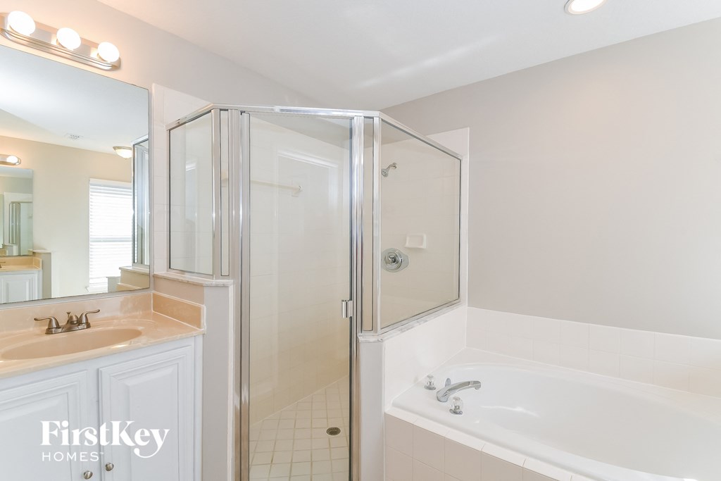 A white bathroom with a sink, mirror, and bathtub.