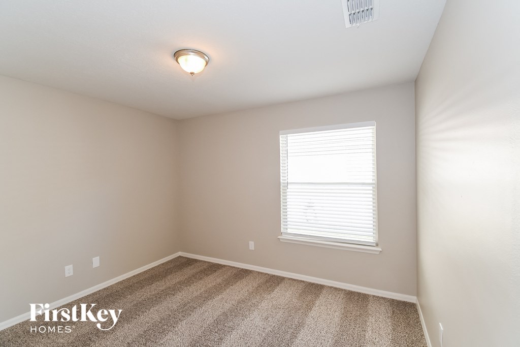 A room with a carpet floor and a window with blinds.