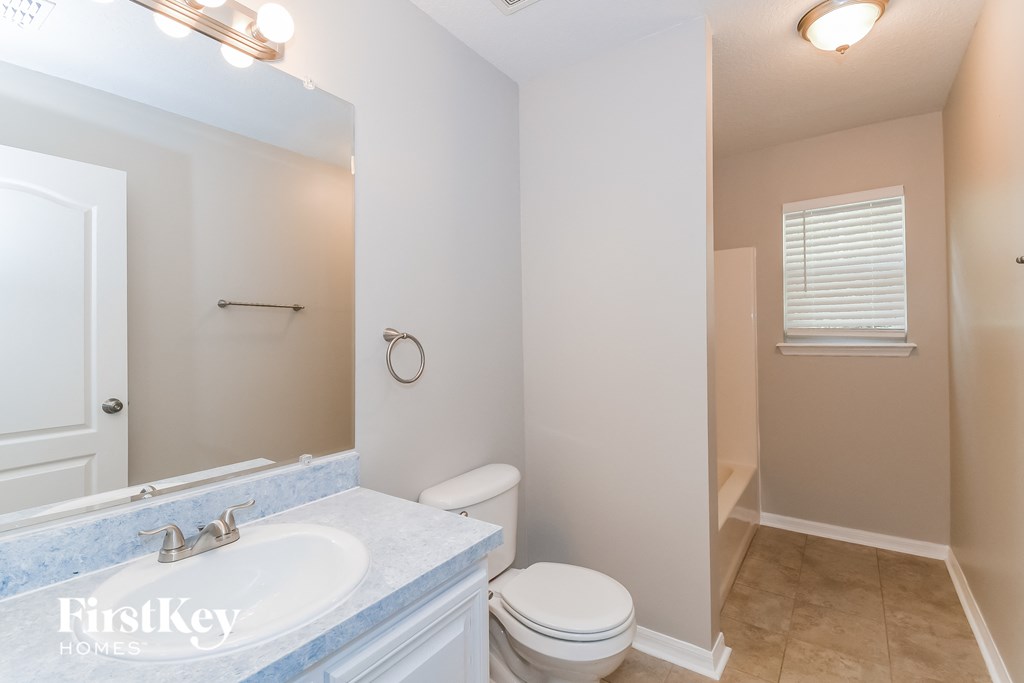 A bathroom with a toilet, sink, and mirror.