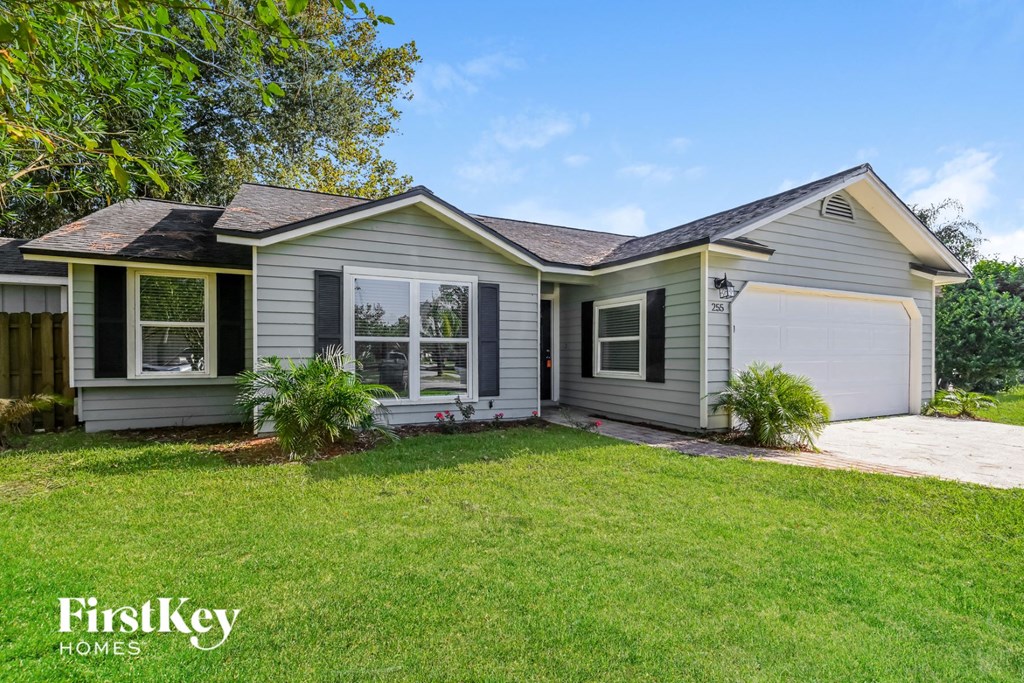 a small gray house with a lawn and a garage
