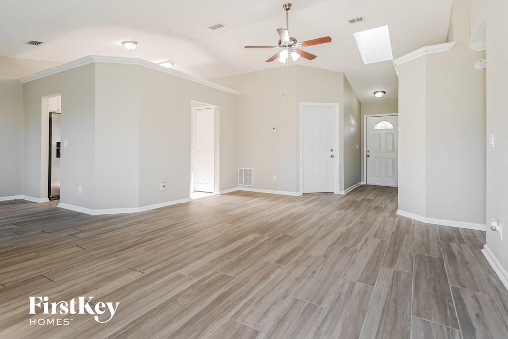 the living room of a new home with white walls and a ceiling fan