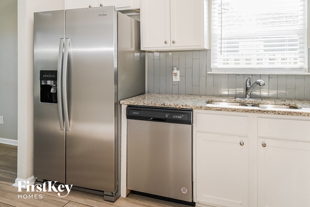 a kitchen with white cabinets and a stainless steel refrigerator