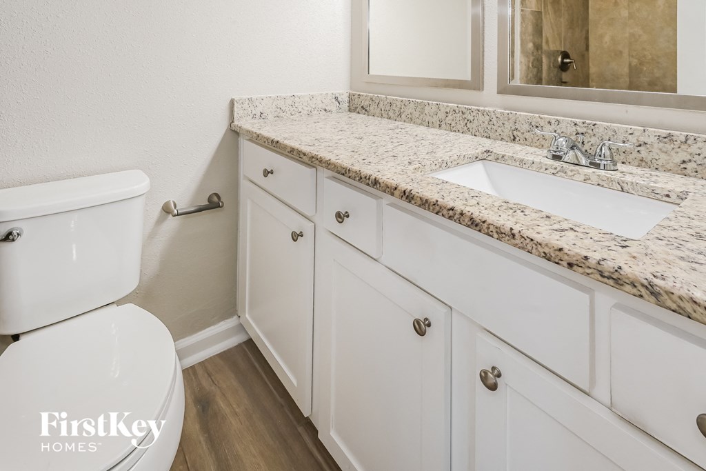 a bathroom with white cabinets and a sink and a toilet