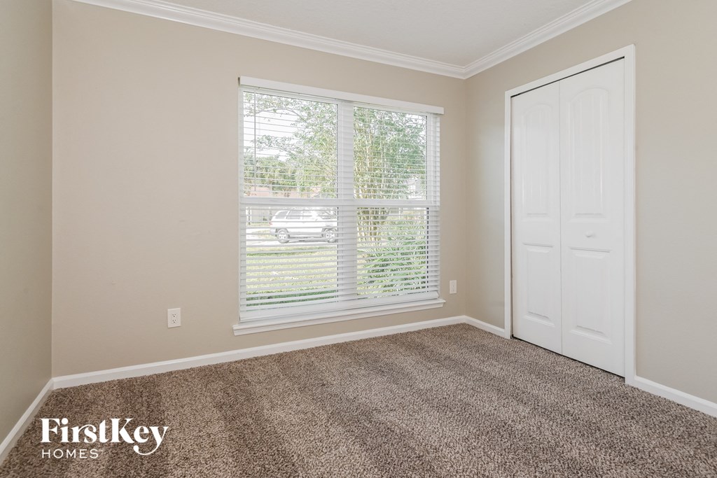 a bedroom with carpet and a large window and a white door