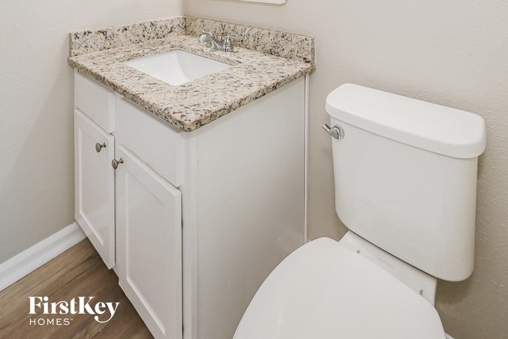 a bathroom with a toilet and a sink with granite counter top