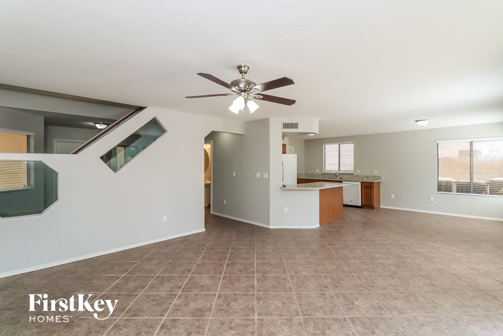 a large living room with a ceiling fan and a kitchen