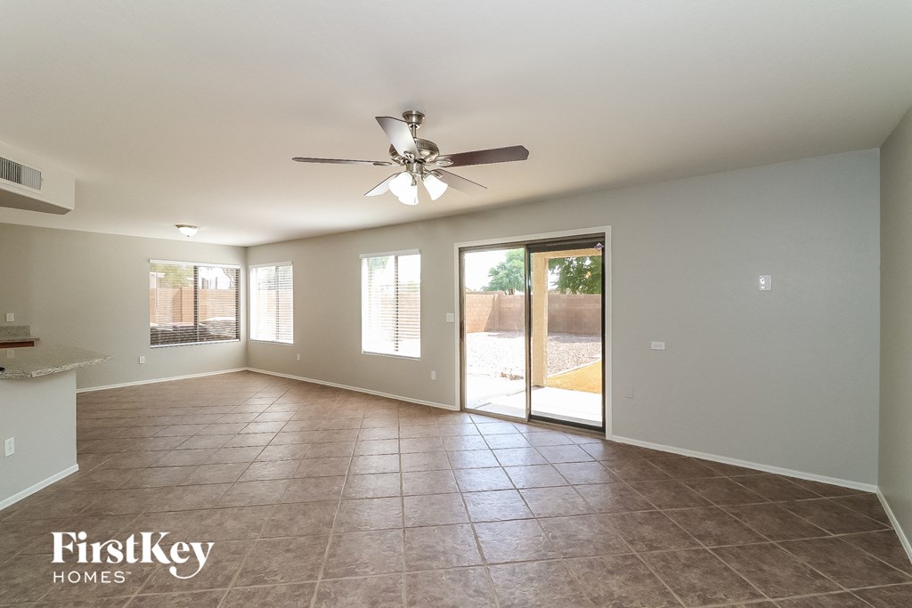 an empty living room with a ceiling fan and a door to a patio