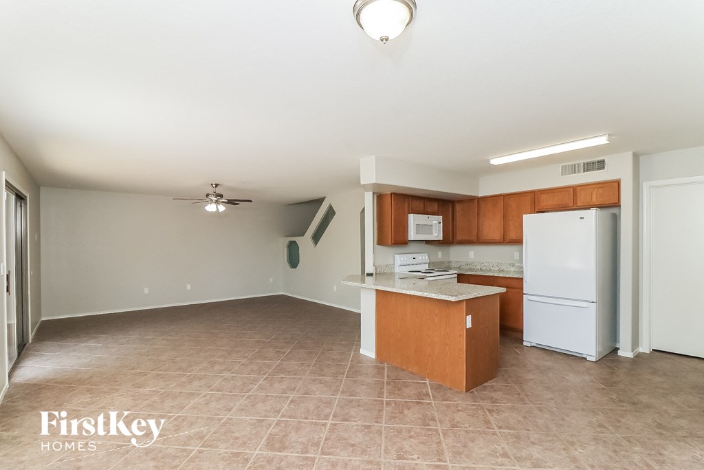an empty kitchen with a white refrigerator and a counter top