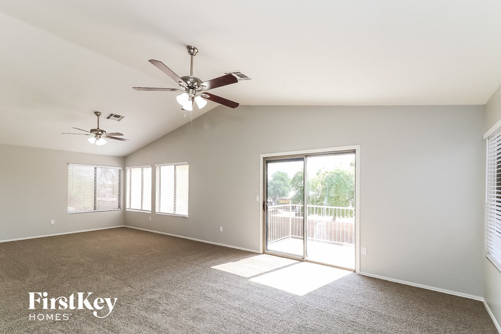 a living room with a ceiling fan and a door to a balcony