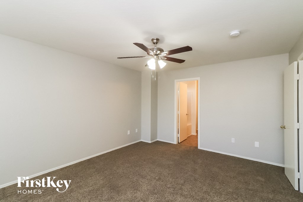 a living room with a ceiling fan and a carpet