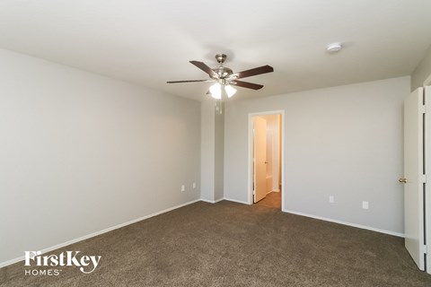 a living room with a ceiling fan and a carpet