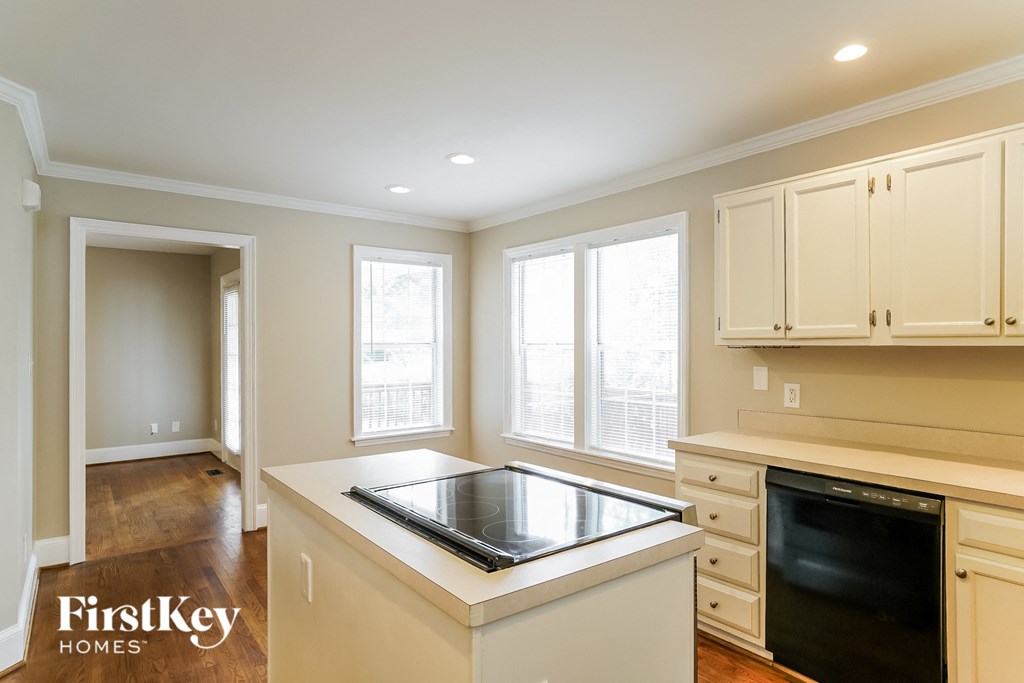 a kitchen with white cabinets and an island with a stove and windows