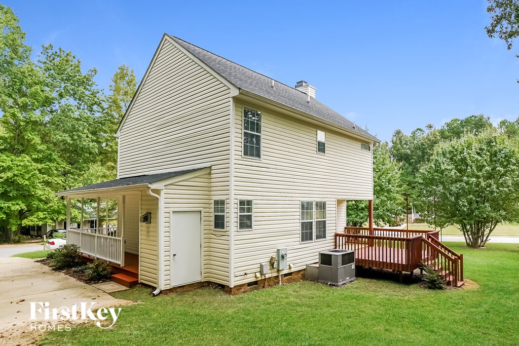 a small white house with a deck and a wood deck