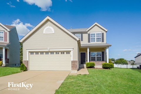 a beige house with a white garage door and a green lawn