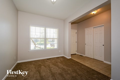 the living room of an empty home with white doors and a window