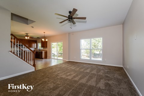 an empty living room with carpet and a ceiling fan
