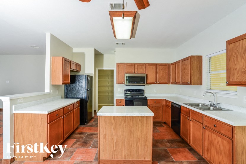 a kitchen with wooden cabinets and black appliances and white counter tops