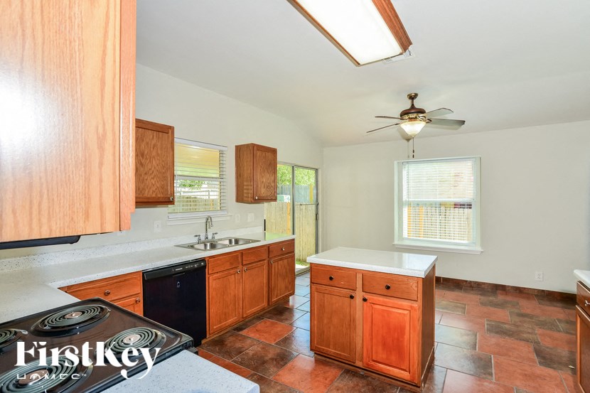 a kitchen with wooden cabinets and a sink and a ceiling fan