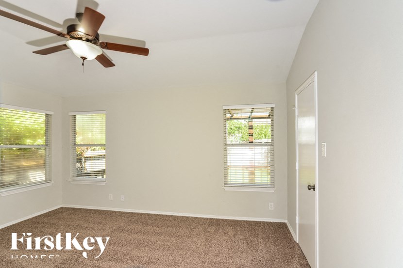 a bedroom with a ceiling fan and three windows