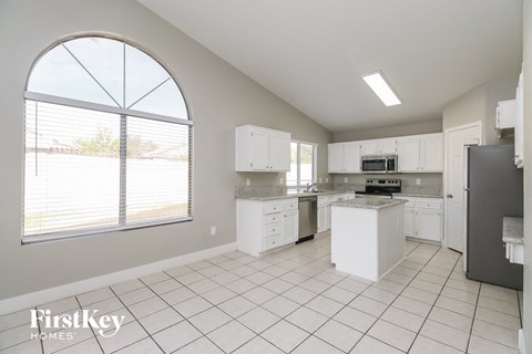 a large kitchen with white cabinets and a large window