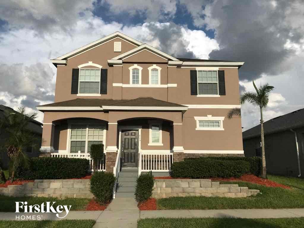 A two-story house with a brown and beige exterior and a black front door.