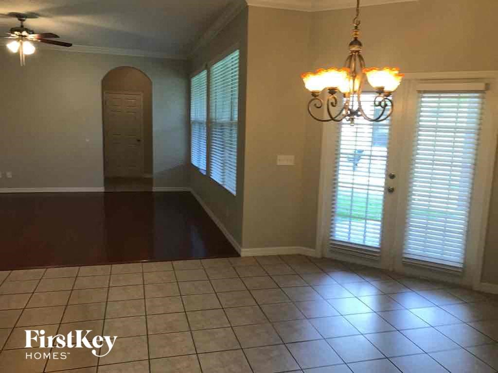 A room with a chandelier, a ceiling fan, and a door with blinds.