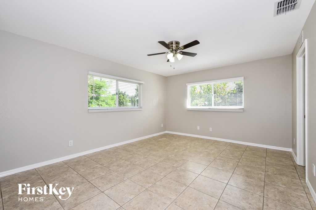 an empty living room with a ceiling fan and a tiled floor