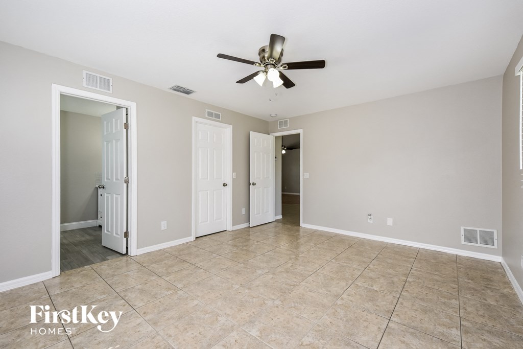 an empty living room with a ceiling fan and a tiled floor