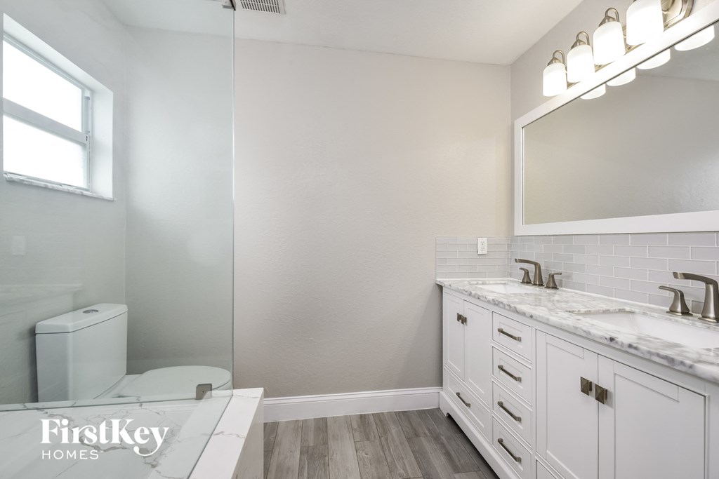 a white bathroom with a toilet and a sink and a mirror