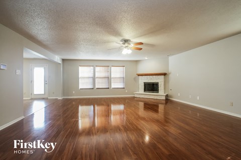 A spacious room with wooden floors and a fireplace.