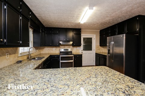 A kitchen with black cabinets and a granite countertop.