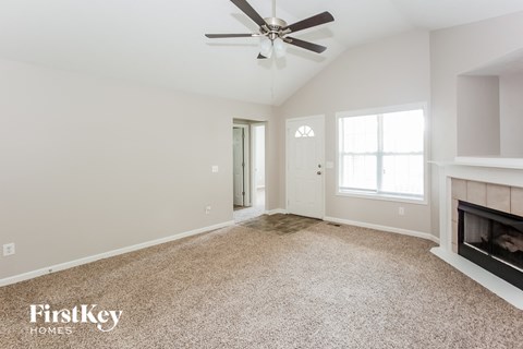 A spacious living room with a fireplace and a ceiling fan.