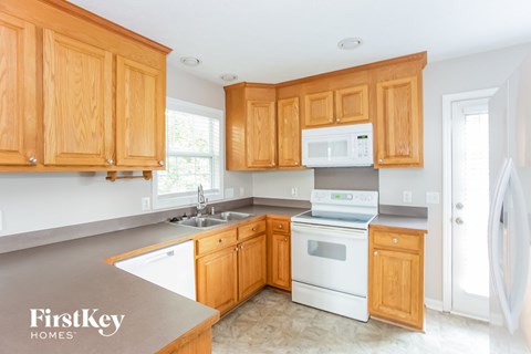 A kitchen with wooden cabinets and a white stove top oven.
