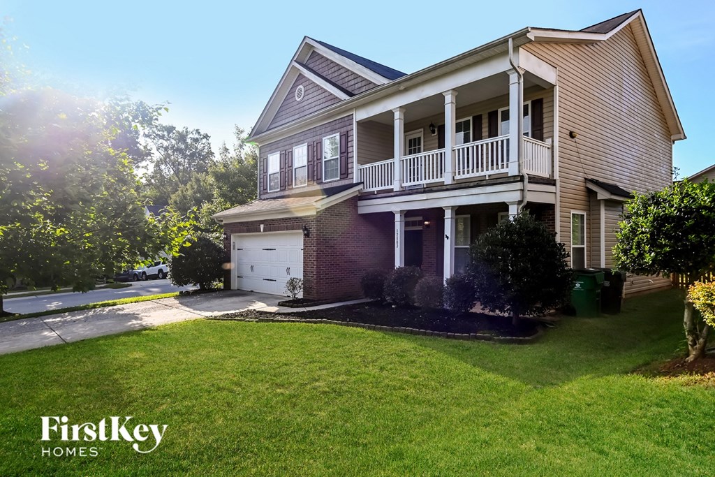 a house with a white garage and a balcony on top of a yard