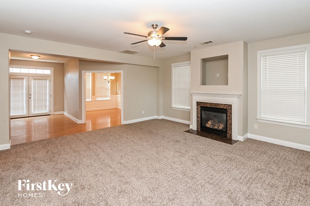 an empty living room with a fireplace and a ceiling fan