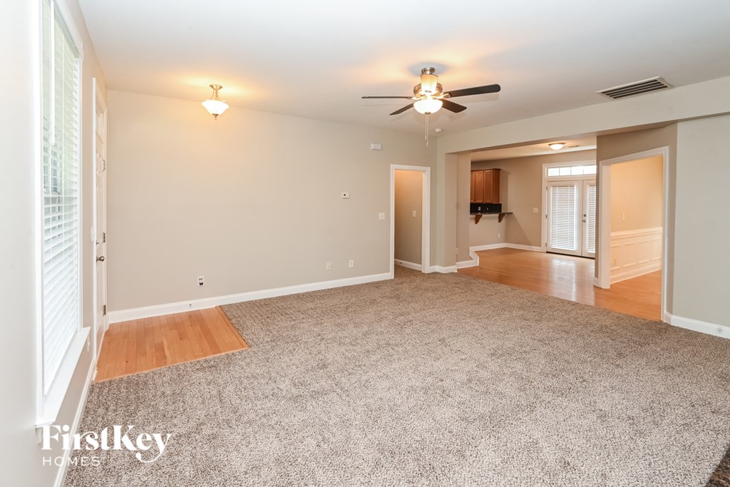 a living room with a carpeted floor and a ceiling fan