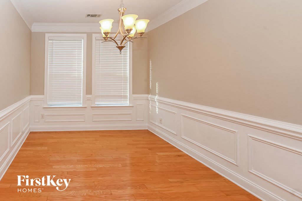 a dining room with white walls and wooden floors and a chandelier