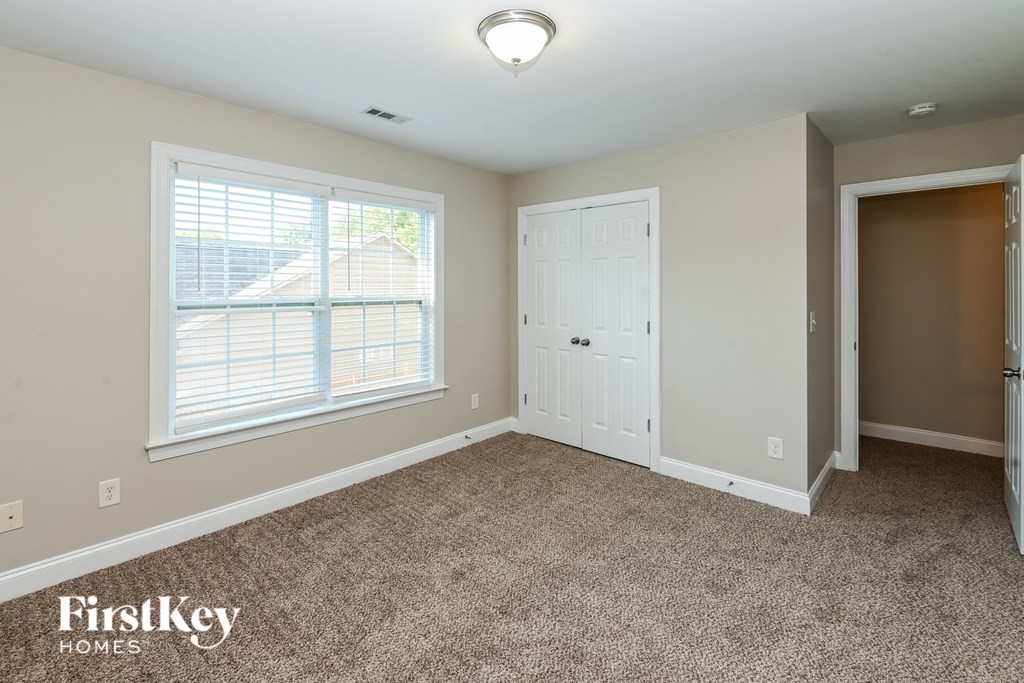 a bedroom with carpet and a door and a window