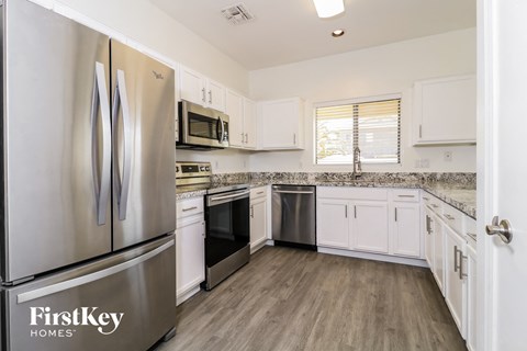 A kitchen with a stainless steel refrigerator and wooden floors.