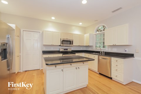 a large kitchen with white cabinets and black counter tops