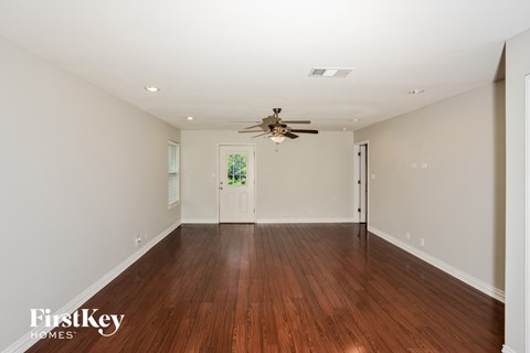 A spacious room with wooden floors and a ceiling fan.