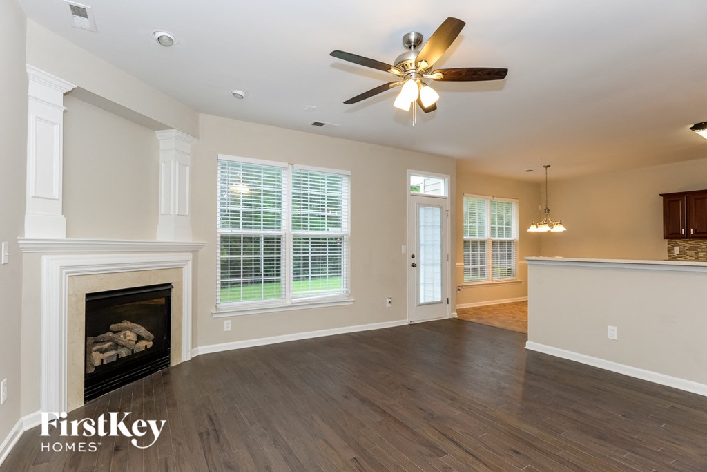 A spacious living room with a fireplace and a ceiling fan.