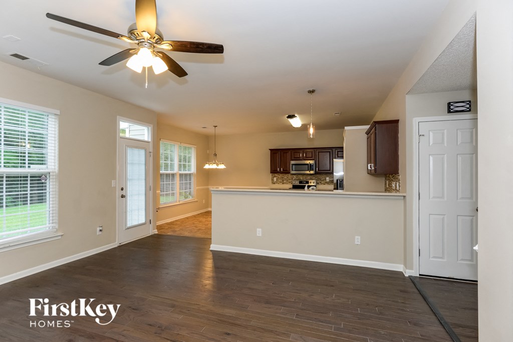 A spacious kitchen and living room with wooden floors and a ceiling fan.