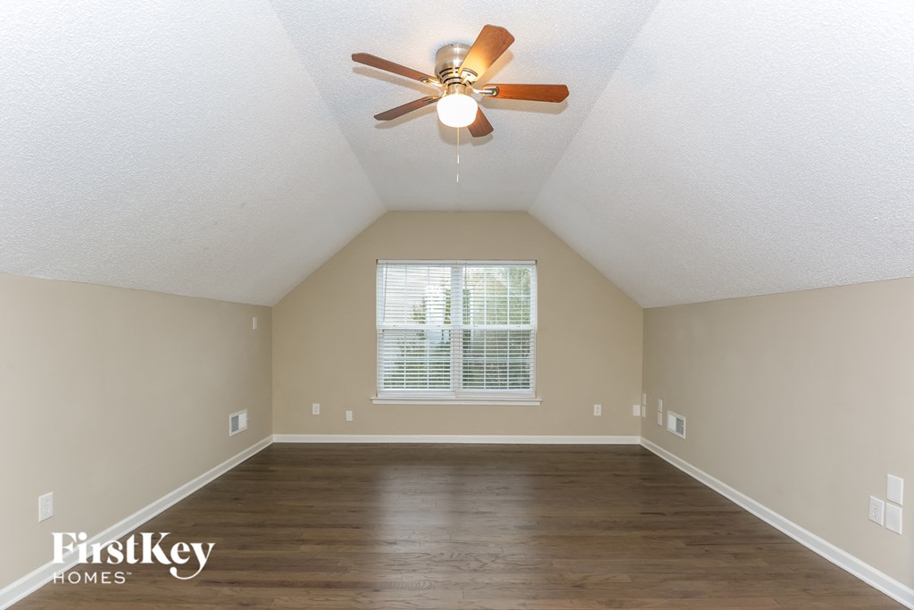 A room with a ceiling fan and a window with blinds.